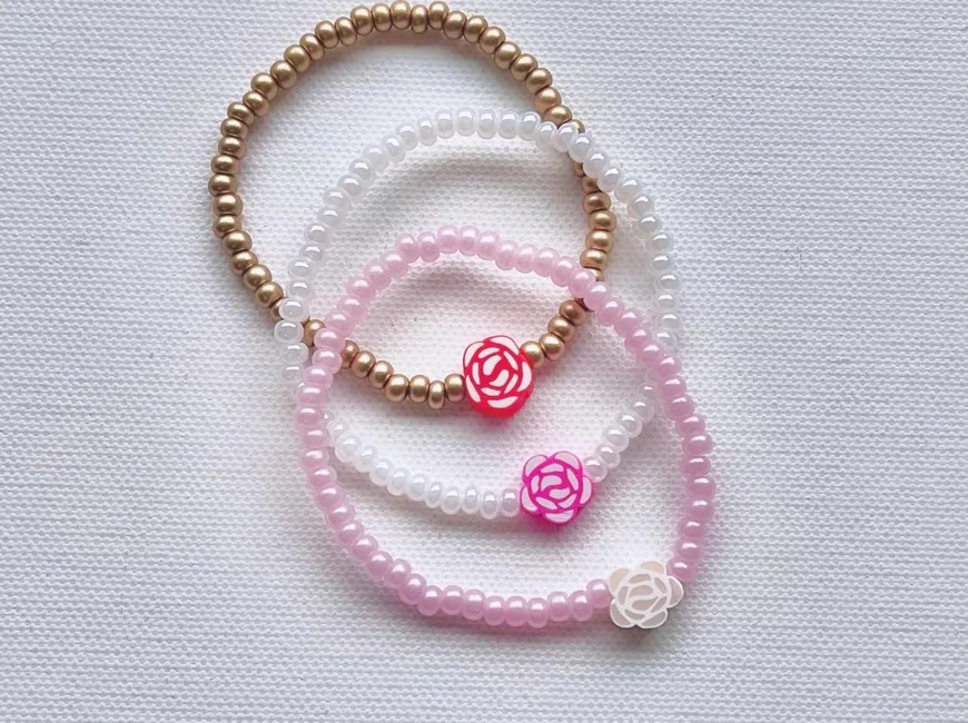 Gold, white and pink seed-bead bracelets finished with small rose charms