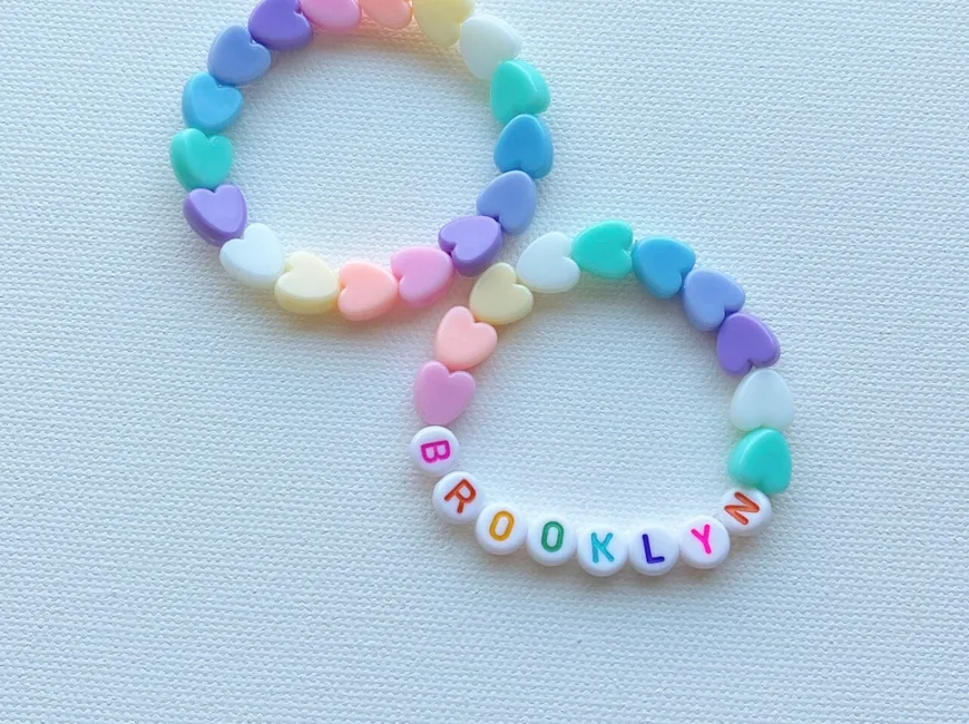 Two pastel heart-bead bracelets, one spelling Brooklyn in white letter beads