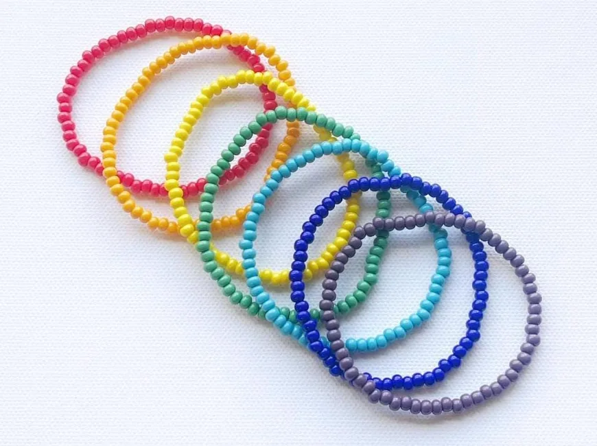A rainbow of seed-bead stretch bracelets fanned out in a row
