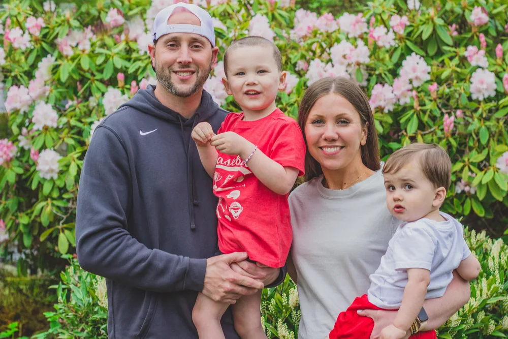 Kendra with her family, smiling in front of pink rhododendrons